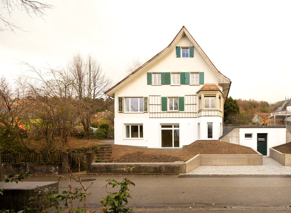Umbau und Ausbau Kellergeschoss zu einer Wohnung mit neuem unterirdischem Kelleranbau mit von der Strasse zugänglichem Veloabstellraum. Im Keller war vorher eine Garage und Abstelläume. Vergrösserung der Fenster. Absenkung der Bodenplatte für mehr Raumhöhe. dazu mussten die Aussenwände unterfangen werden mit neuen Fundamenten.