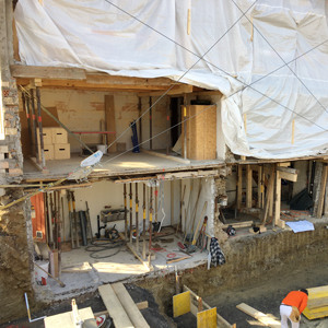 Baustellenfoto Umbau Flarzhaus Stäfa mit Ersatzneubau Scheune. Die Scheune wird bewohnbar gemacht. Die neue Unterkellerung ist relativ anspruchsvoll, da das 200 jährige Flarzhaus ohne Fundamente auf instabilen, losen Steinmauern in das Erdreich gebaut wurde. Der neue Keller wird tiefer liegen als der bisherige Flarzhauskeller und komplett aus Beton gefertigt, da er das bestehende Flarzhaus statisch stützen wird. Ab Bodenplatte Erdgeschoss wird der Ersatzneubau ein reiner Holzbau sein. nijo architekten Zürich, Nina & Johannes Wick